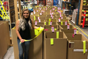 Veronica Krylova standing in front of numerous boxes of fluorescent yellow trim