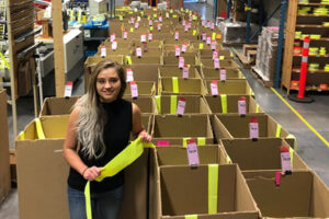 Veronica Krylova standing in front of numerous boxes of fluorescent yellow trim
