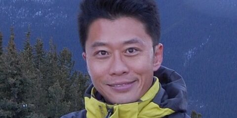 Hyun-Joong Chung standing in front of a mountain landscape